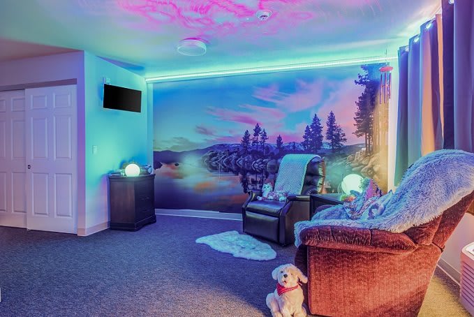 A cozy and modern room with neon lights, vibrant wall art, and comfortable seating.
