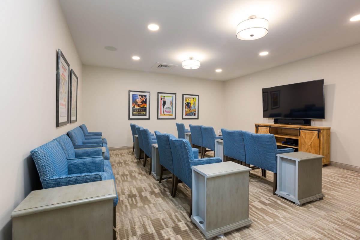 A modern theater room with blue seating and a large screen ready for viewing.