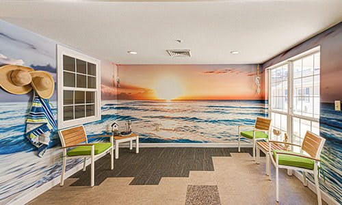 A waiting room with a sunset ocean mural and modern seating.