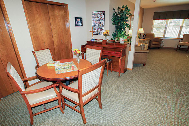 Cozy living space with a round table, chairs, and a piano.