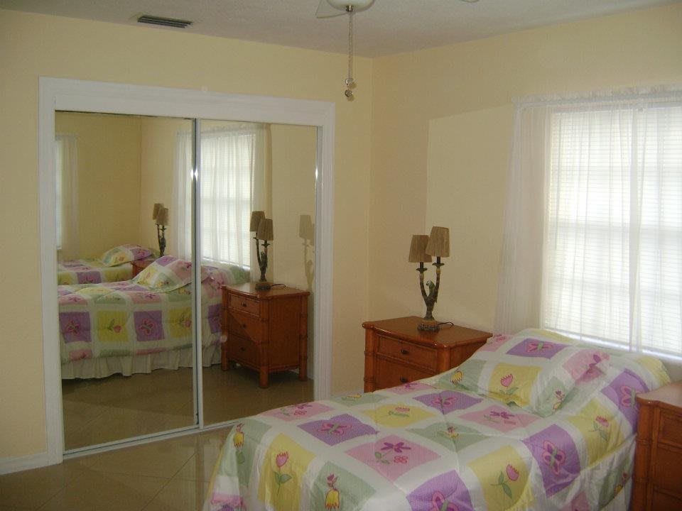 A cozy bedroom with pastel bedding, a mirrored closet, and elegant table lamps.
