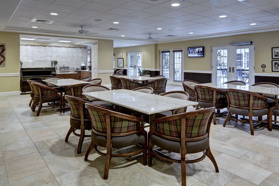 A spacious dining area with tables and chairs, featuring a television and warm lighting.