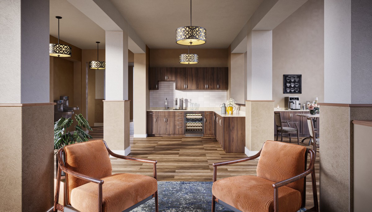 A modern open-plan kitchen and living area featuring wooden cabinets, two orange armchairs, and a stylish chandelier.