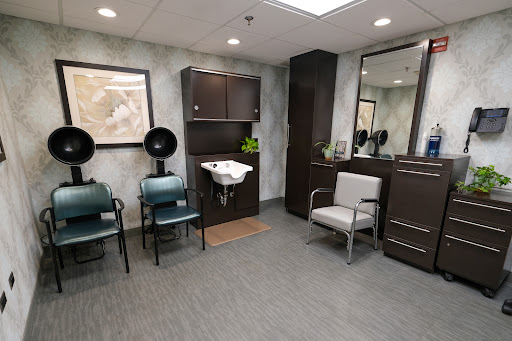 A stylish and modern waiting area in a salon, featuring comfortable seating and hair drying stations.