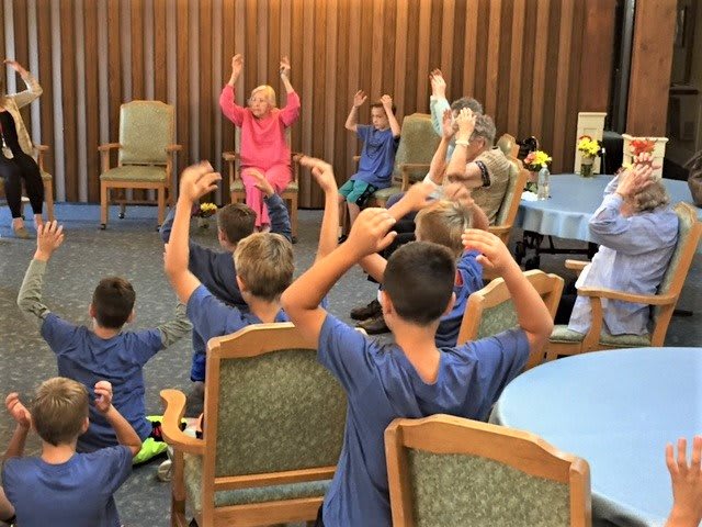 Children participating in an activity with elderly individuals in a communal setting.