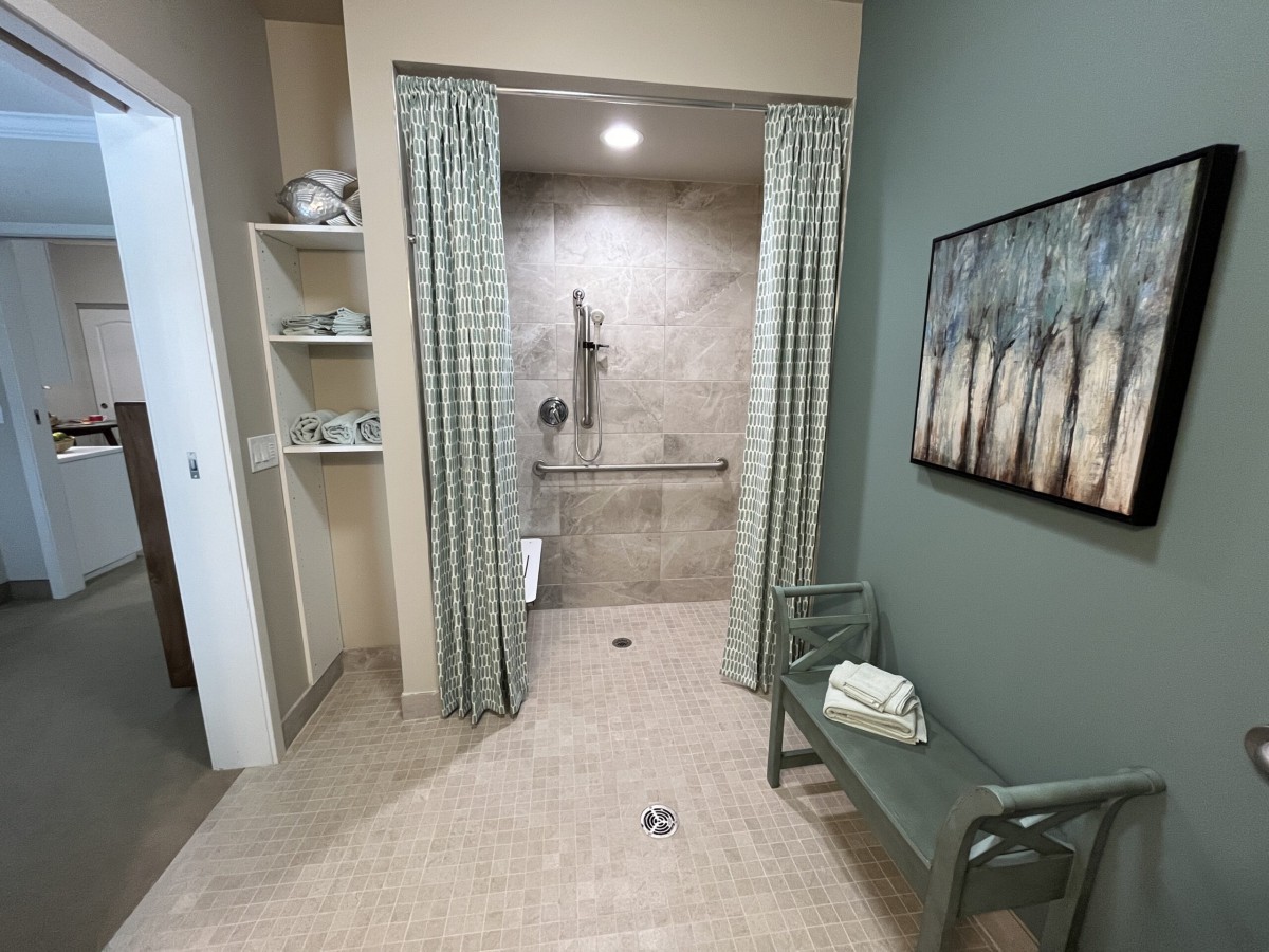 A modern bathroom with a spacious shower area, curtains, and neatly organized shelves.