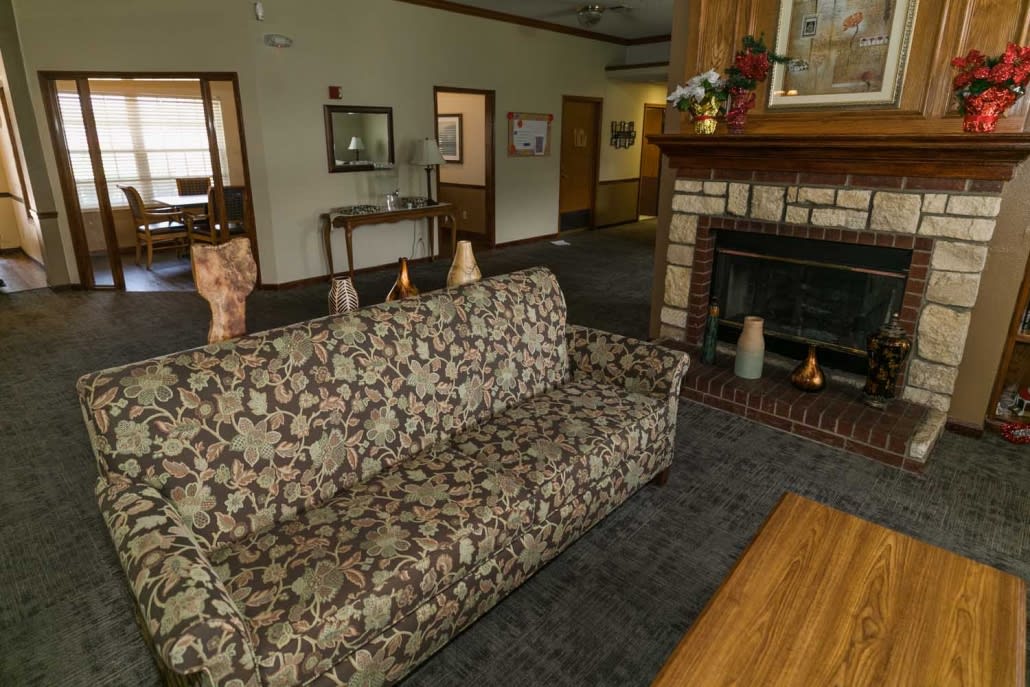 A traditional living room featuring a patterned couch and a classic fireplace.