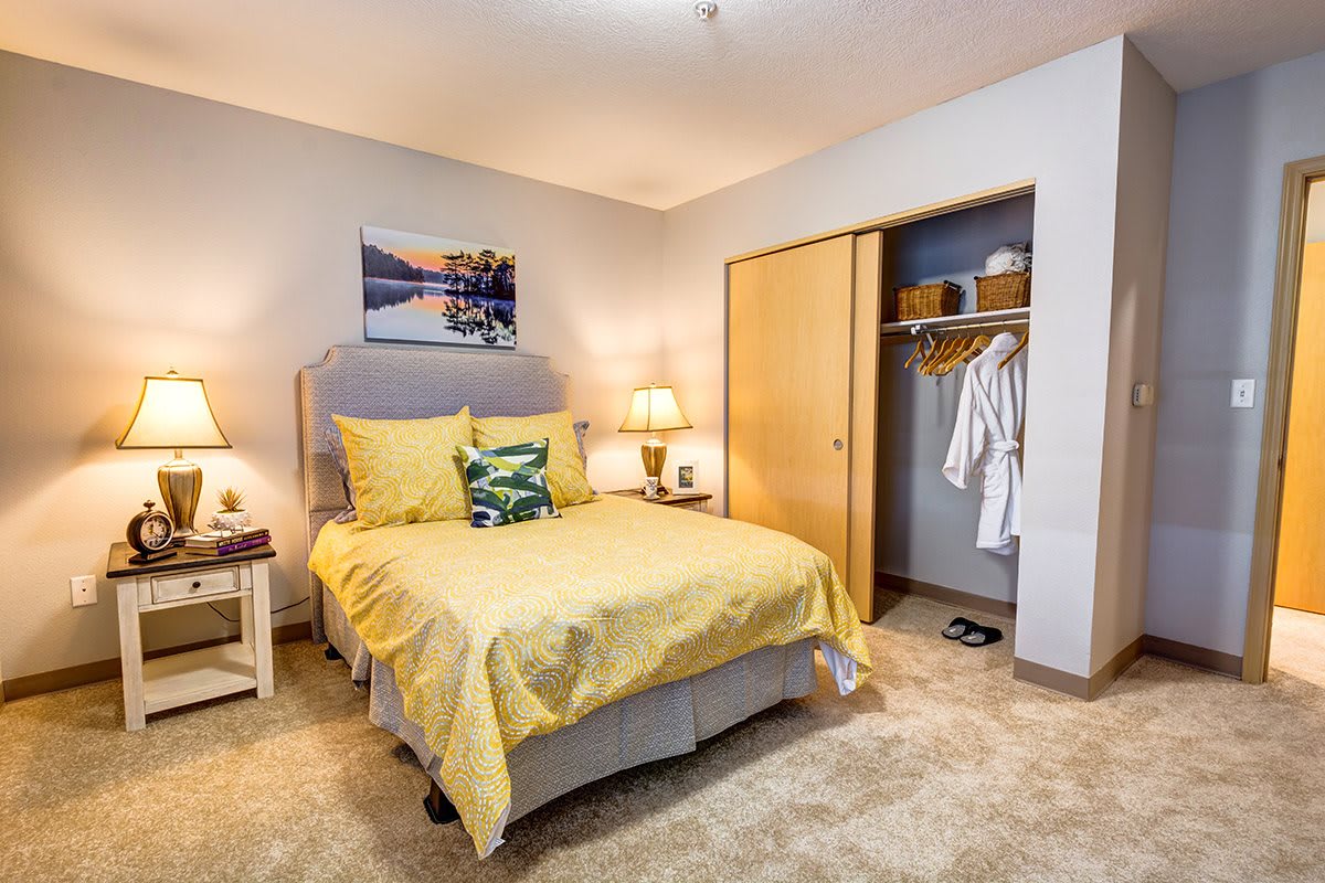 A cozy bedroom with yellow bedding and an open closet.