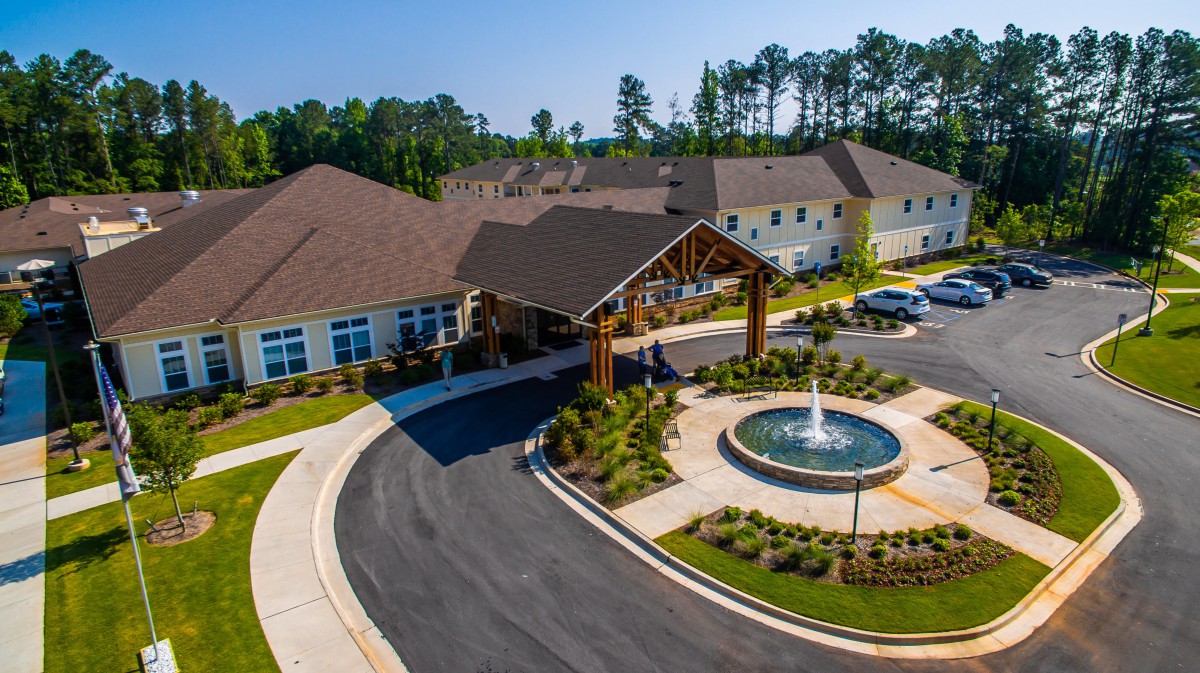 Aerial view of a building with a circular driveway and fountain at the entrance.