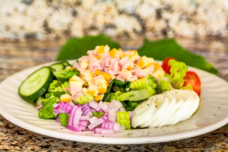 A colorful salad with fresh vegetables and fish on a plate.