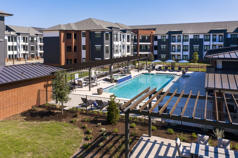 A modern apartment complex featuring a large swimming pool and landscaped outdoor area.