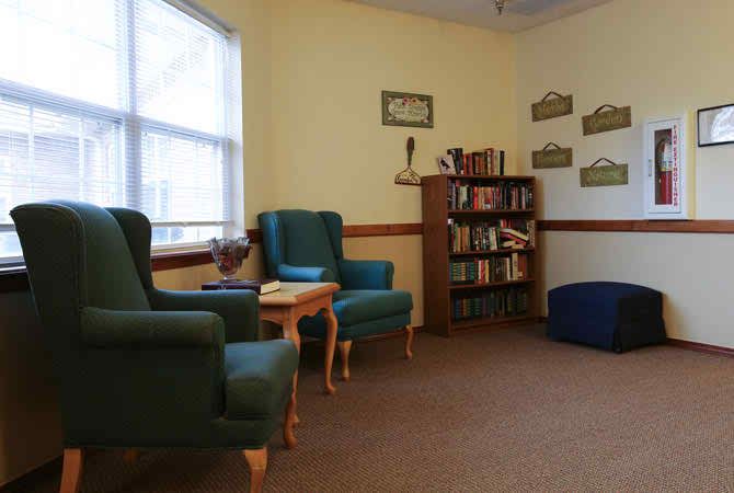 A cozy reading room with armchairs and a bookshelf near the window.