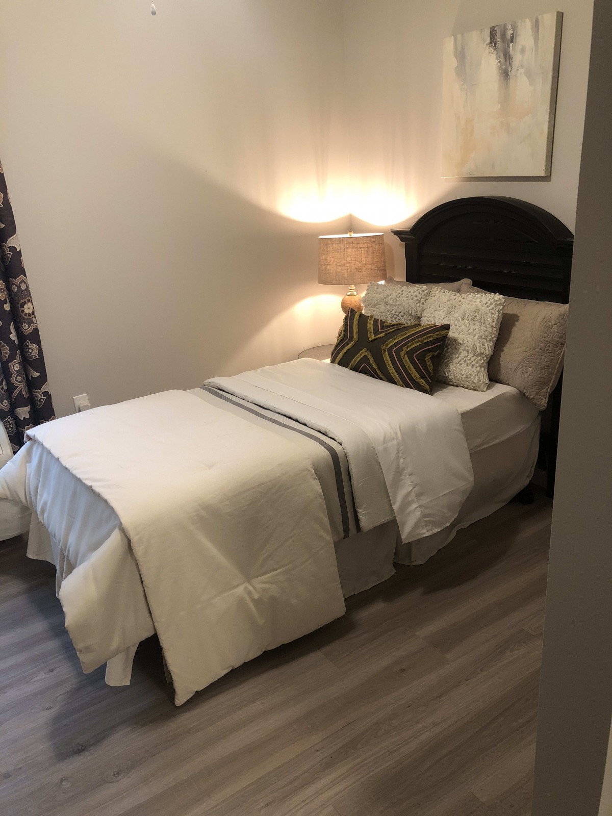 A cozy bedroom with neatly arranged bedding and a warm lamp on the side.