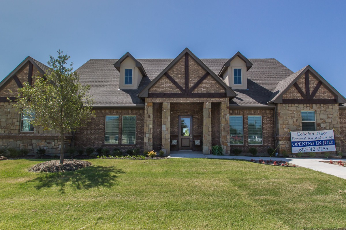 A brick suburban house with a neatly maintained lawn and a clear blue sky.
