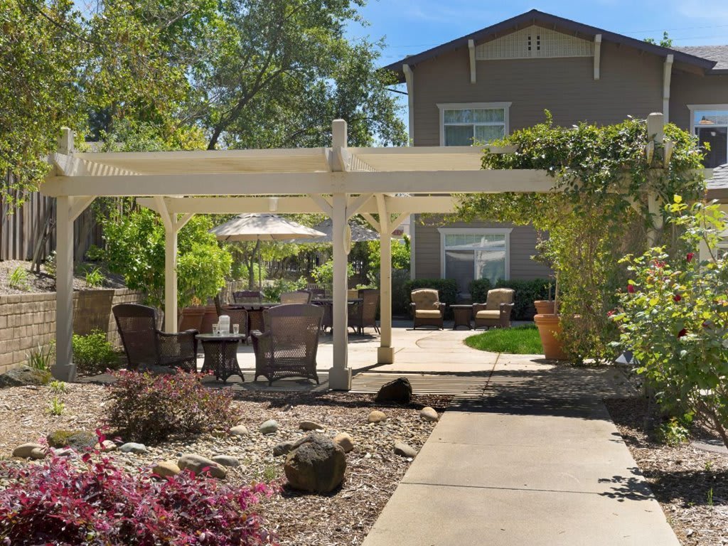 A beautiful backyard patio with a pergola and outdoor seating, surrounded by lush landscaping.