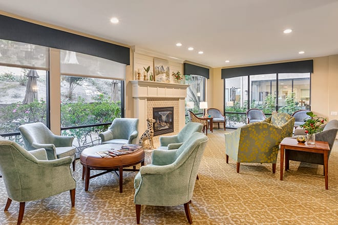 A cozy and bright living room with comfortable seating, a fireplace, and large windows.