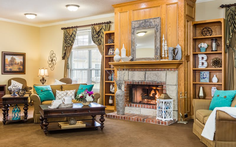 A cozy living room featuring a wooden fireplace, decorative mirror, and elegant furnishings.