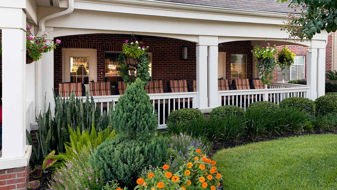 A charming porch surrounded by a well-maintained garden with vibrant flowers.