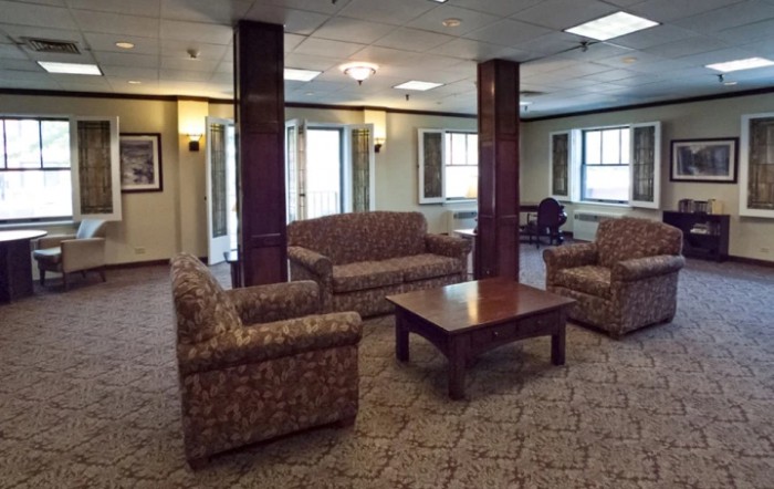 A lounge area with sofas, chairs, and a coffee table on a carpeted floor.