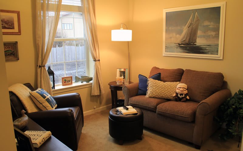 A cozy living room with a sofa, armchair, and warm lighting.