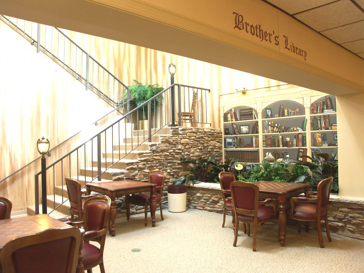 A cozy interior space featuring a staircase, tables, chairs, and decorative plants.