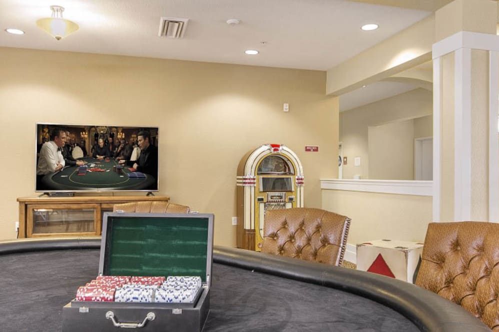 A cozy game room featuring a poker table with chips, a television, and a classic jukebox for entertainment.