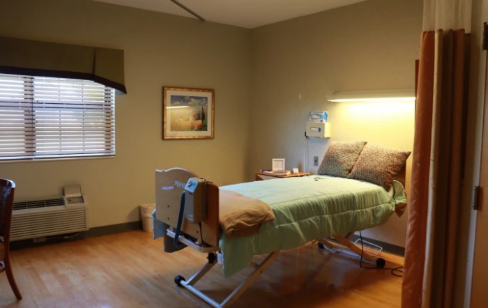 A well-lit hospital room with a single bed and basic amenities.