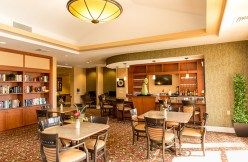 A cozy restaurant interior with neatly arranged tables and chairs, featuring warm lighting and a small bar area.