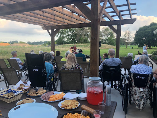 Residents enjoy a lively outdoor performance with snacks in a serene setting.