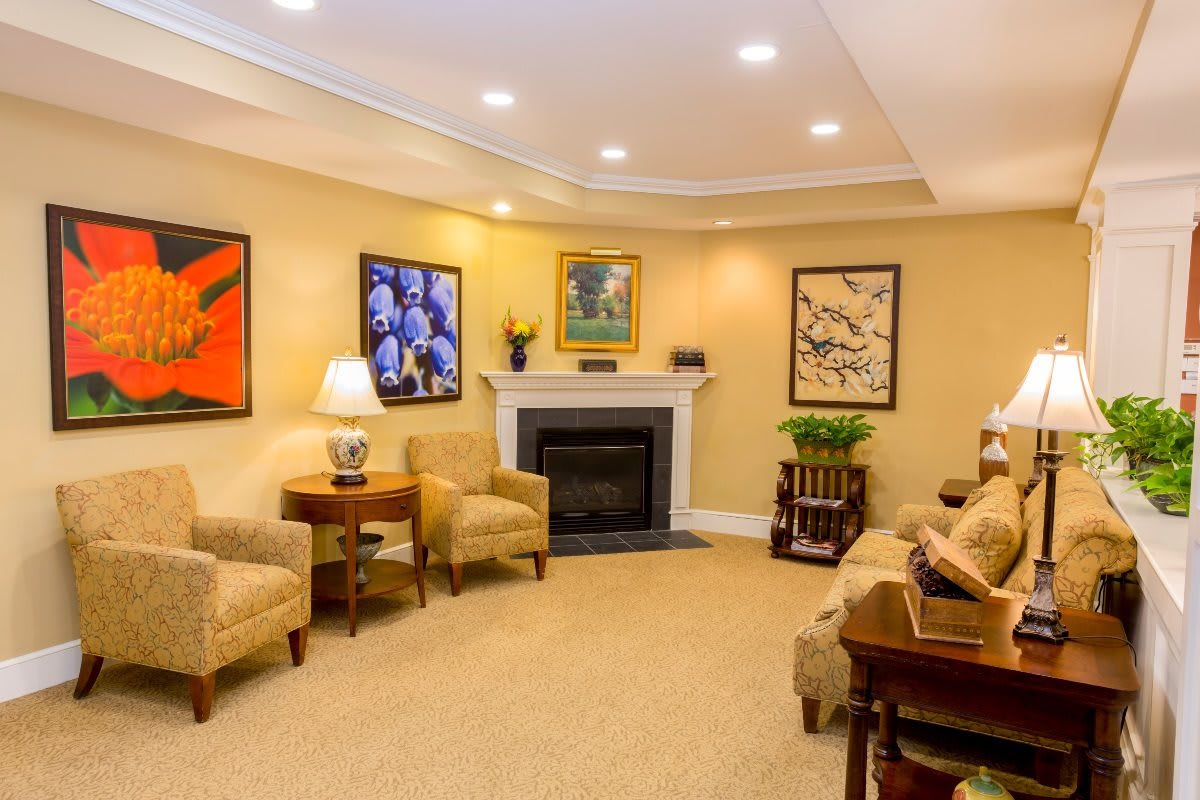 A cozy living room featuring a central fireplace, surrounded by comfortable seating and adorned with various artworks.