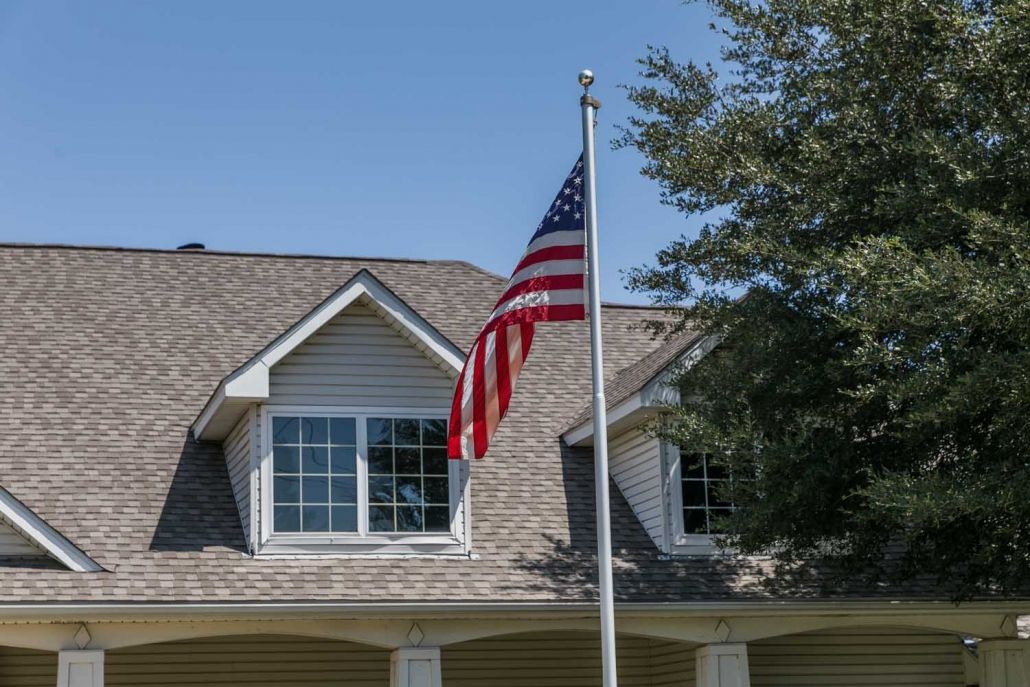 A suburban house with an American flag flying outside under a clear blue sky.