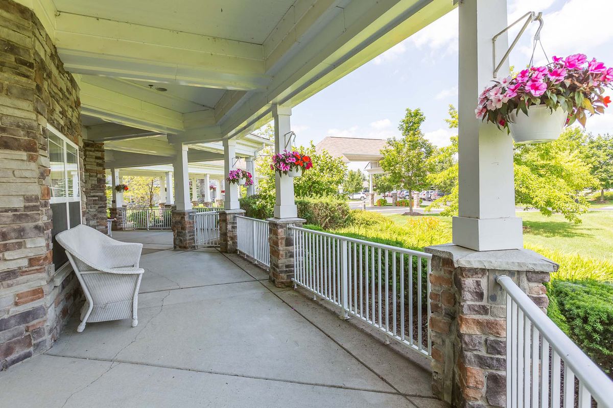 A sunny porch with hanging flower baskets overlooking a garden path.