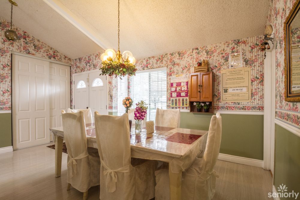 A cozy dining room with elegant furniture and floral wallpaper.