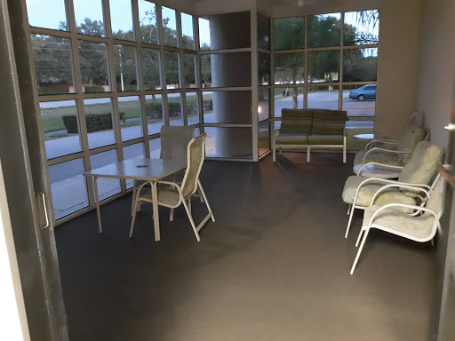 A modern waiting area featuring several chairs and large glass windows allowing natural light.