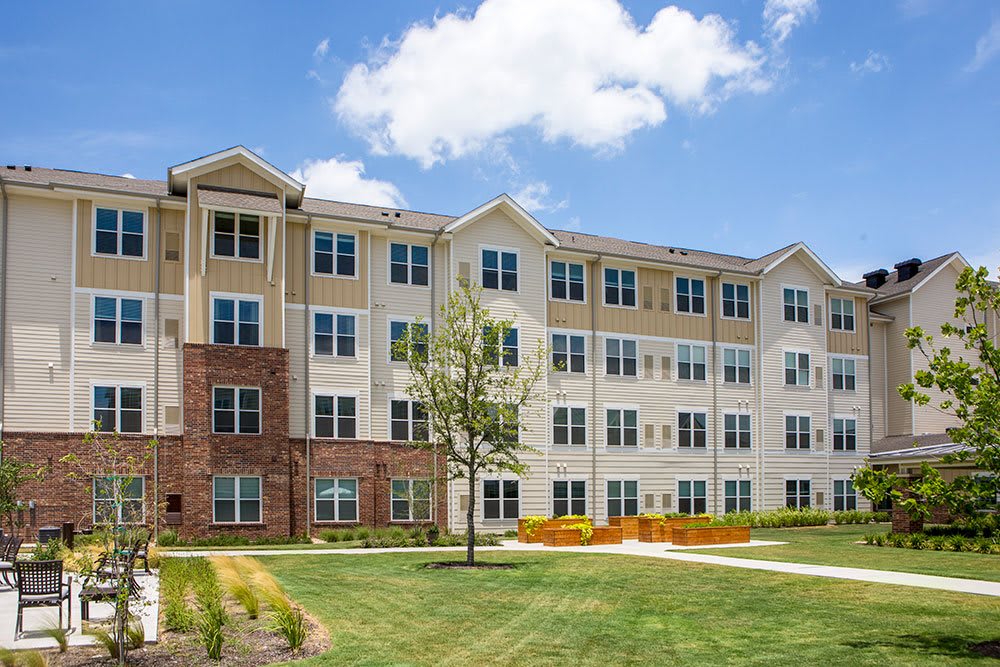 A modern apartment building with well-maintained landscaping and clear blue skies.