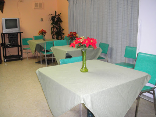 A cozy dining area featuring green tables and chairs, adorned with a floral centerpiece.
