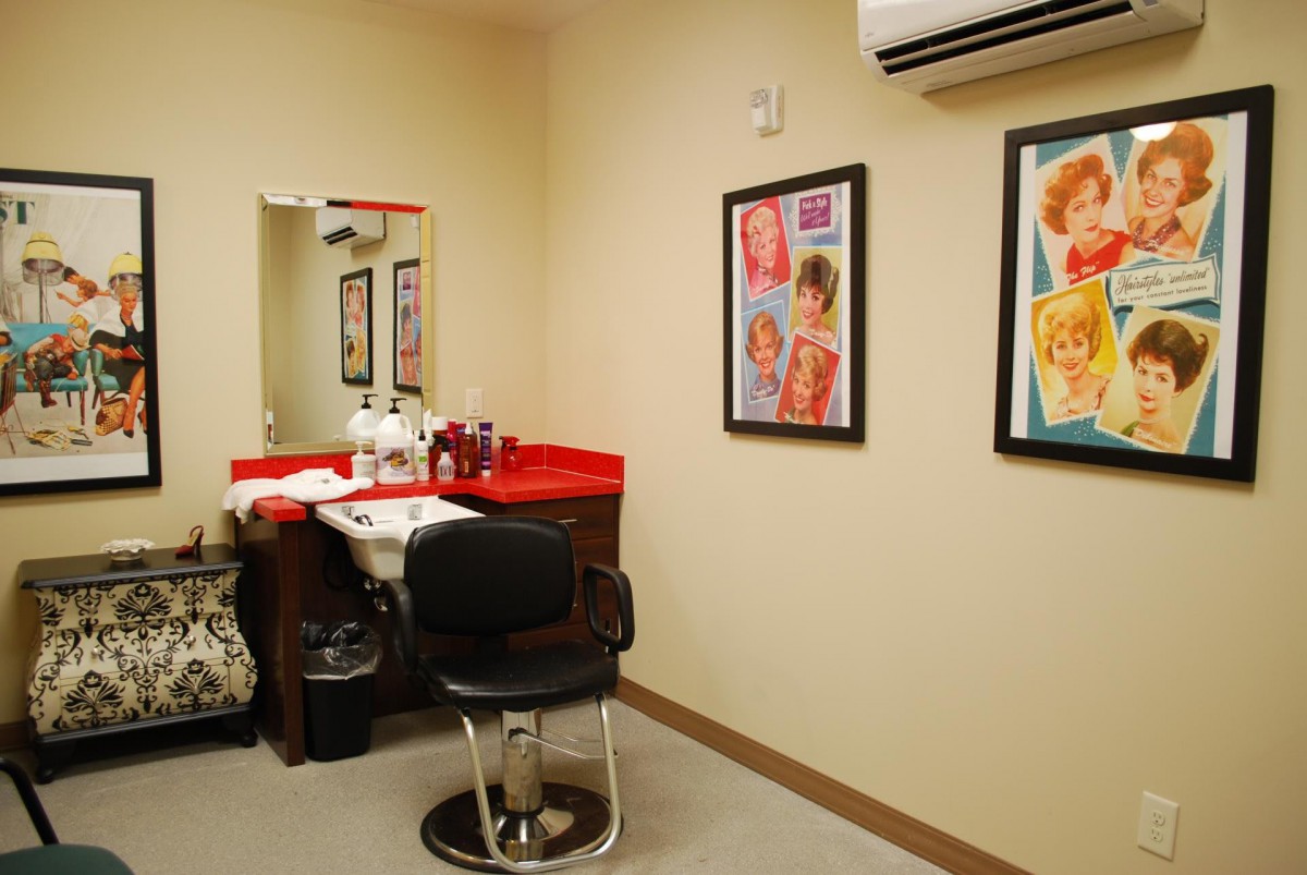 Interior of a hair salon with a chair, mirror, and hair products on the counter.