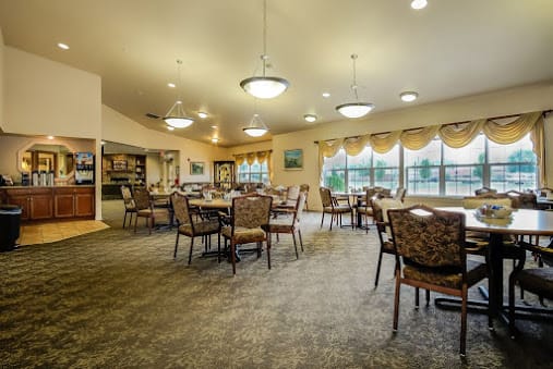 A spacious dining room with multiple tables and chairs, featuring large windows and elegant lighting.