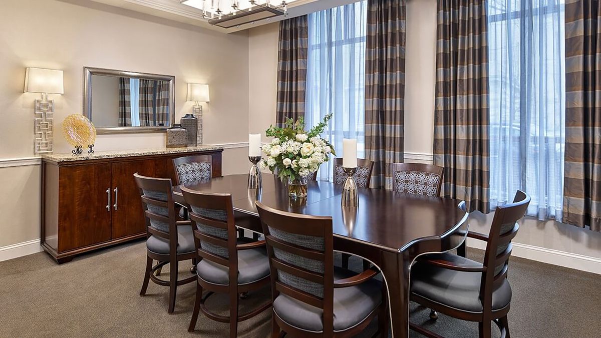 Elegant dining room with a large wooden table, surrounded by chairs and decorated with flowers and candles.