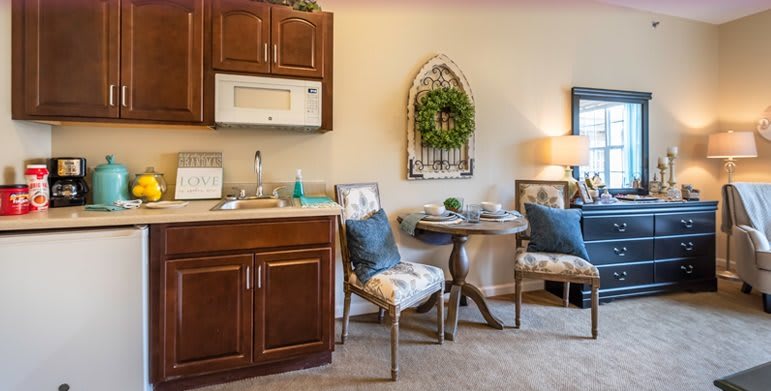 A cozy kitchenette area with wooden cabinets, a small table and chairs, and decorative elements.