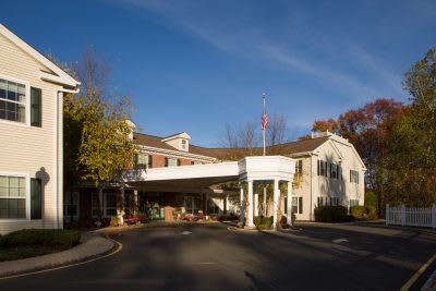 A hotel entrance with a covered driveway surrounded by autumn trees.