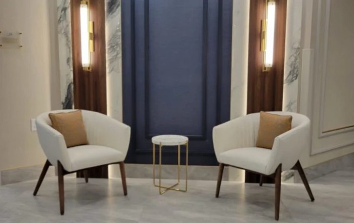 A modern, minimalist seating area with two chairs and a small side table.