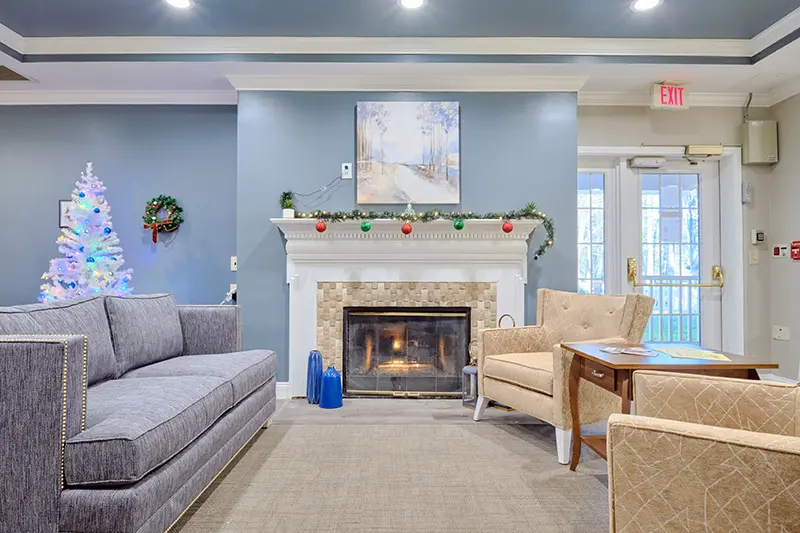 A cozy living room with a fireplace, sofa, and armchairs arranged for comfort.