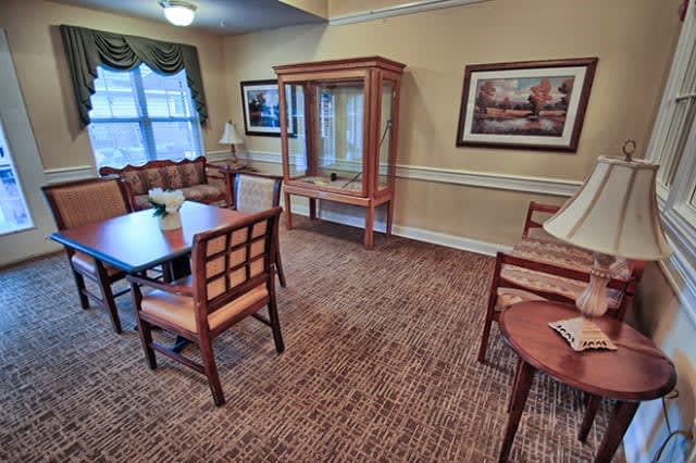 A cozy living room with armchairs, a table, and decorative artwork on the walls.