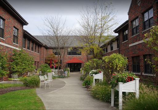 A serene courtyard featuring brick buildings and lush greenery.