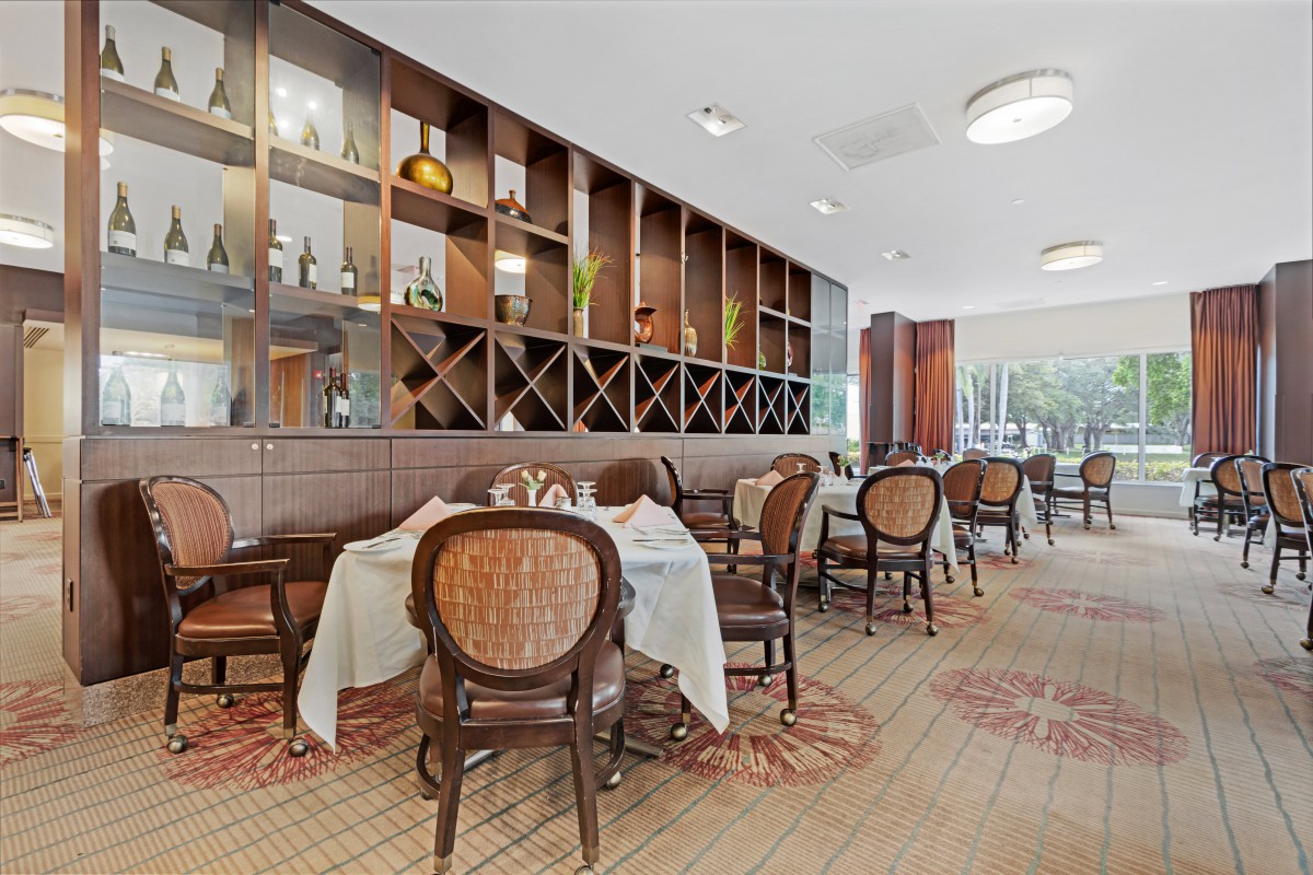 A cozy restaurant interior featuring neatly arranged tables and chairs with decorative shelving on the wall.