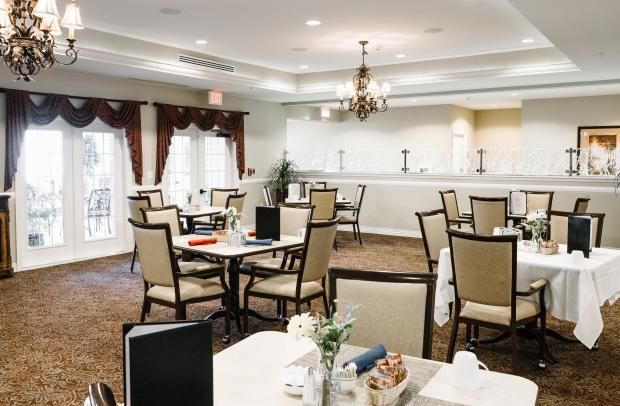 A well-lit dining area with arranged tables and chairs, featuring elegant decor and chandeliers.