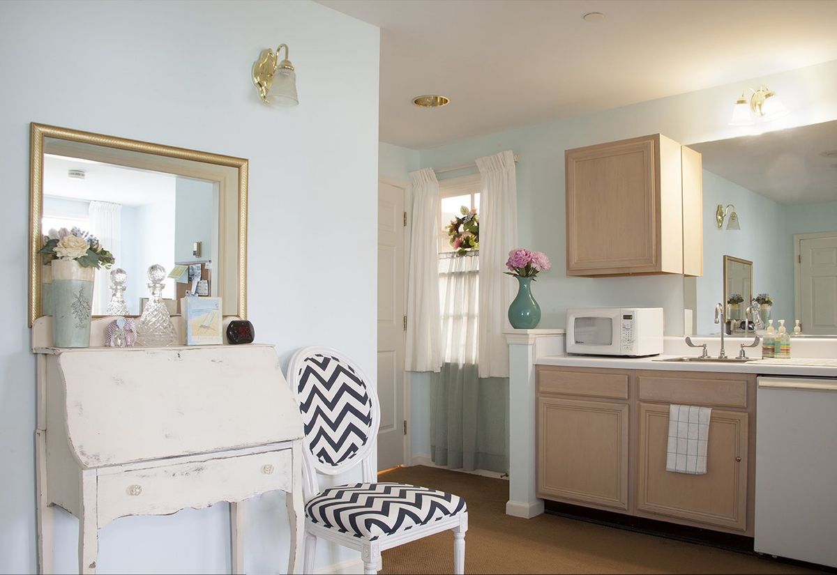 A cozy kitchen corner with a chevron-patterned chair, wooden cabinets, and a vase of flowers.