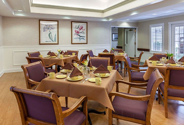 A neatly arranged dining room with tables set for a meal, featuring purple chairs and elegant decor.