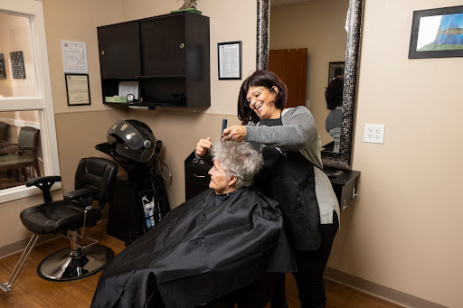 A hairdresser styles the hair of a senior client in a cozy salon setting.
